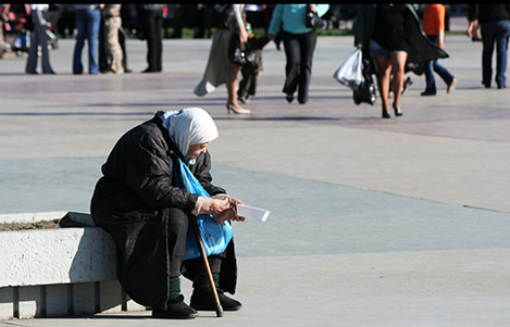 Poor old woman begging an alms on the city square.