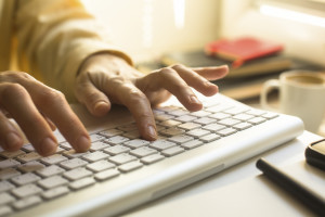 Women's fingers typing on laptop keyboard close-up.