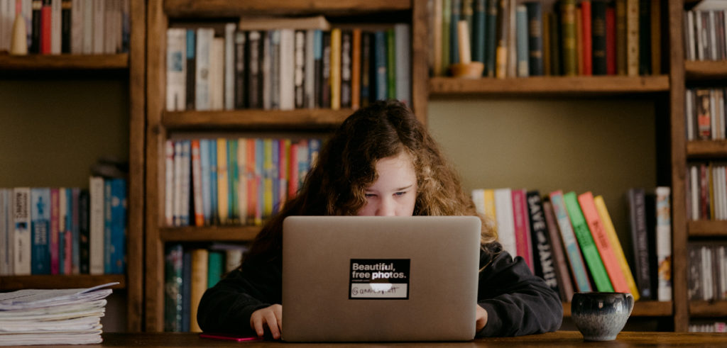 niña viendo su laptop en la biblioteca de su casa