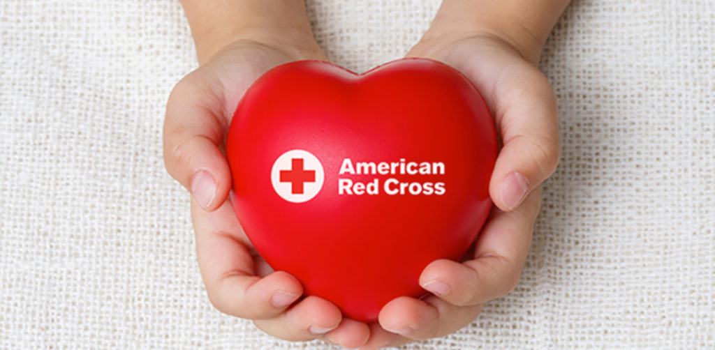 Manos sosteniendo un corazón de la Cruz Roja