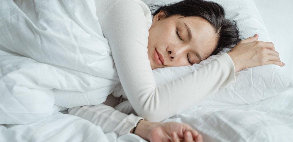 Mujer durmiendo con sábanas blancas