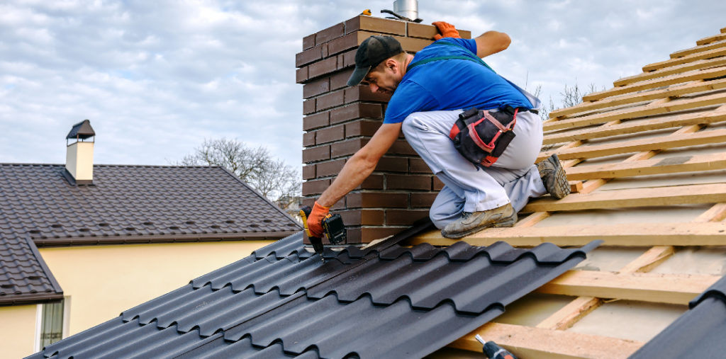 Hombre instalando tejas en el techo de una casa