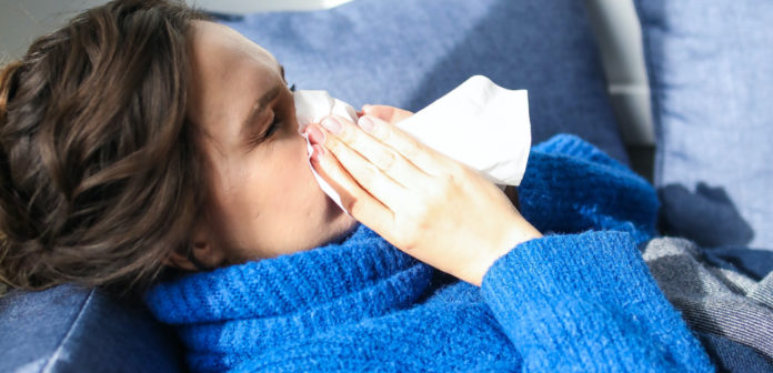 Mujer recostada con síntomas de gripe