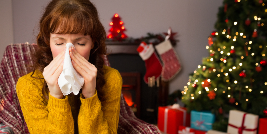 Virus mujer con gripe junto a un árbol de Navidad