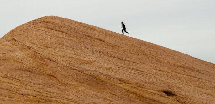 Hombre corriendo hacia la cima de un peñasco