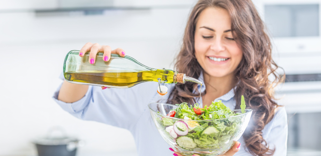Mujer poniendo aceite de oliva en una ensalada