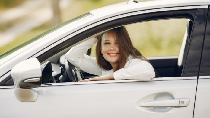 Mujer sonriendo dentro de su auto
