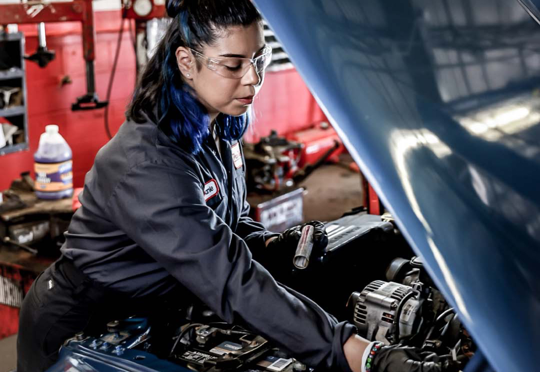 Joven latina trabajando como mecánica de autos