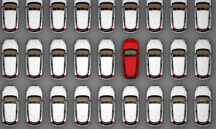Auto rojo entre varios carros de color blanco