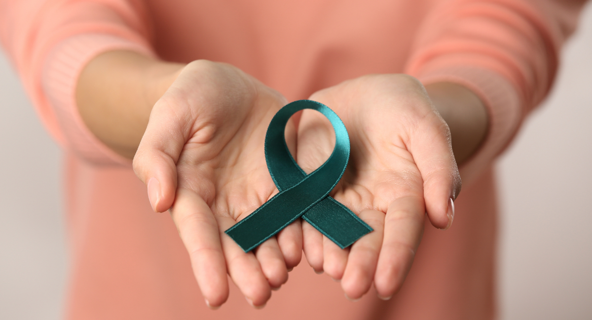 Mujer con el listón símbolo de la lucha contra el cáncer cervical