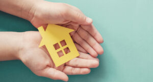 Manos con una casita de papel