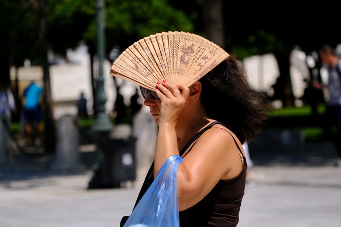 Mujer en la calle cubriéndose con un abanico