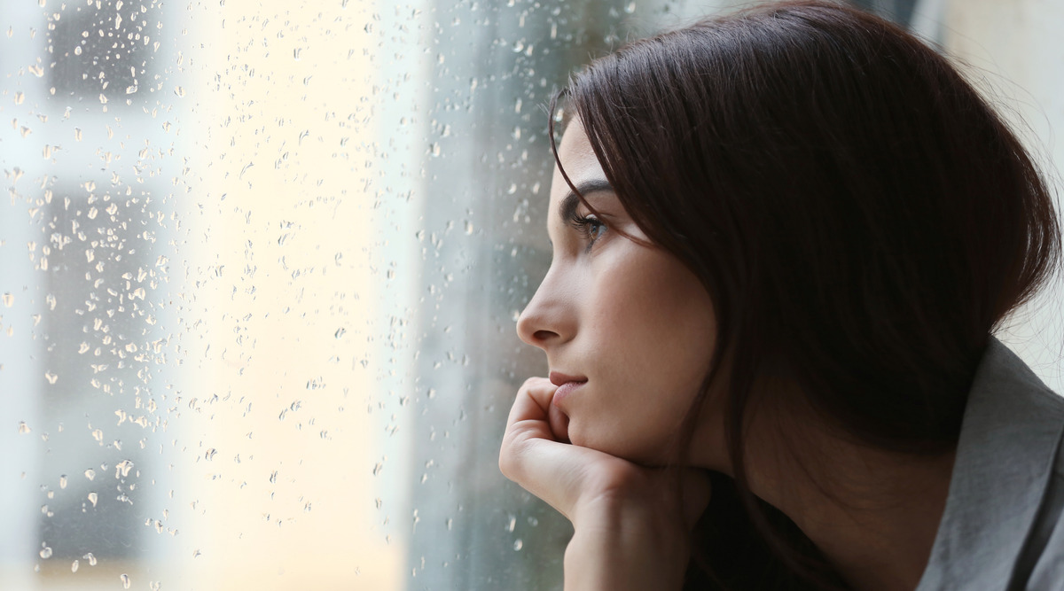 Mujer triste viendo por la ventana