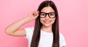 Niña con lentes sobre un fondo rosa