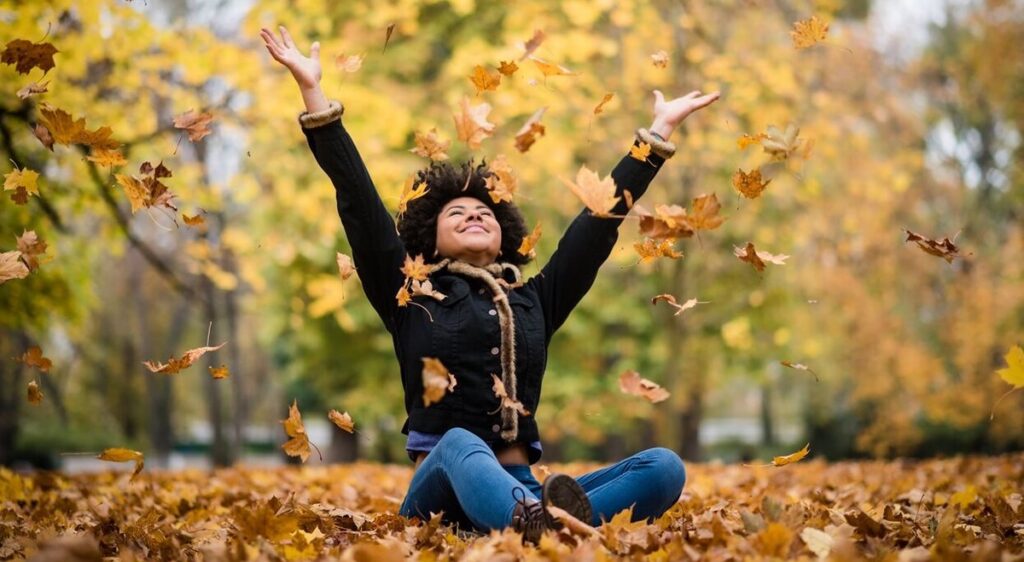 Chica jugando con las hojas del otoño
