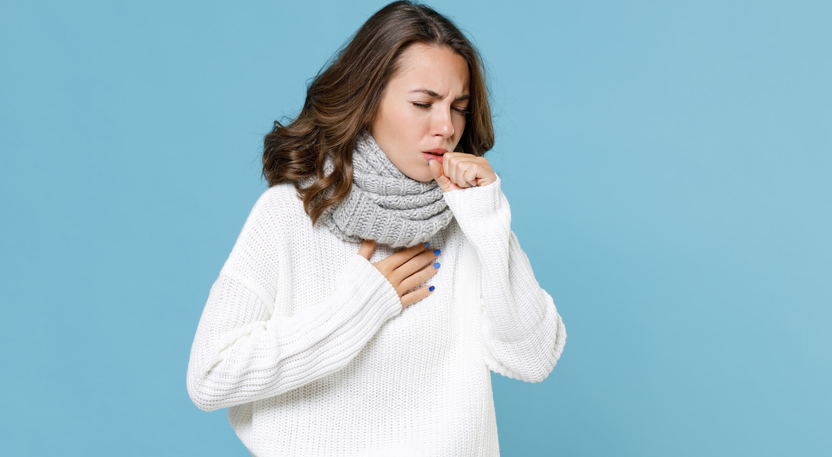 Mujer con suéter blanco tosiendo