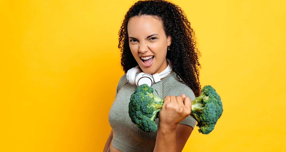 Chica con dos brócolis en forma de una pesa