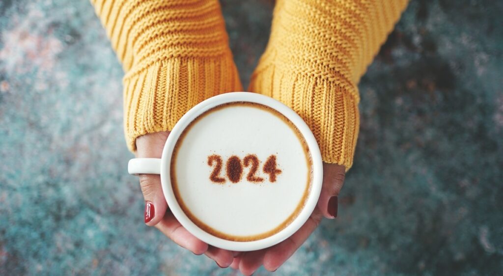 Manos con una taza de café y el número 2024