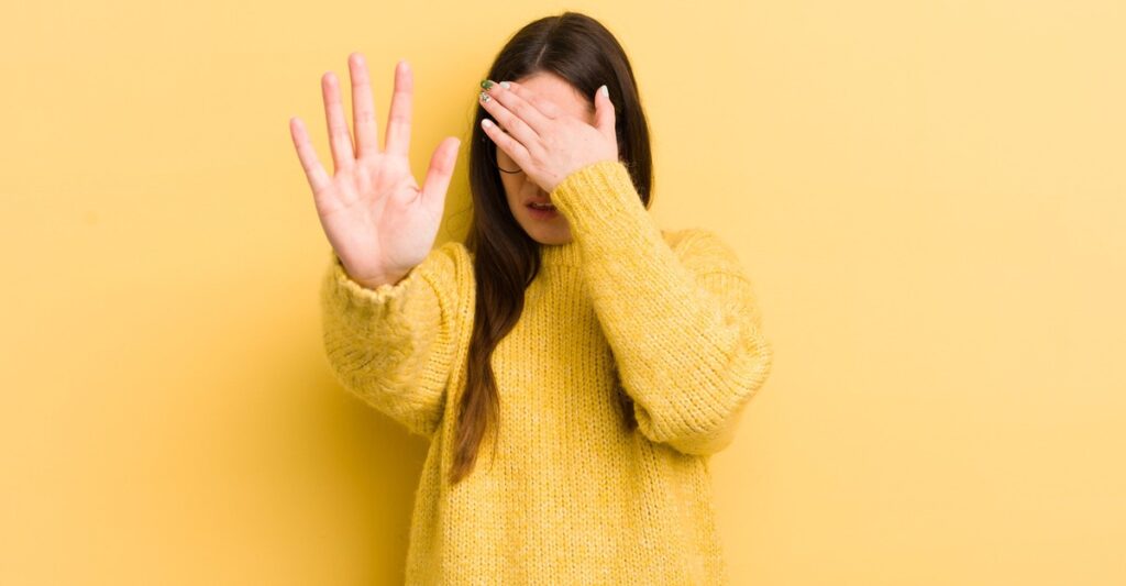 Mujer con suéter amarillo con la mano al frente
